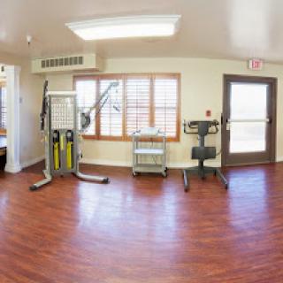 A well-lit indoor gym area featuring various exercise equipment and a cozy atmosphere.