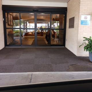 A view of a hotel entrance with glass doors and potted plants.