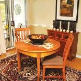 A cozy dining area with a round wooden table and two chairs, set on a patterned rug.