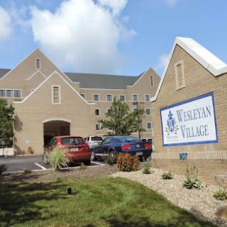 A view of a residential community building with parking and landscaping.