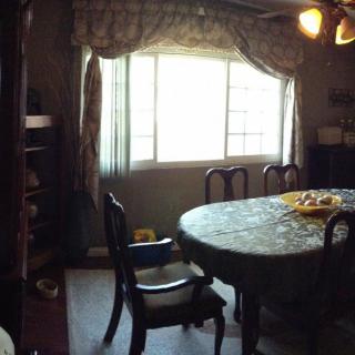 A dining room with a table and chairs near a window adorned with curtains.