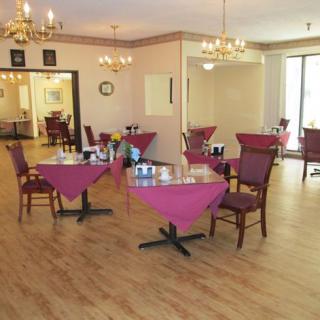A cozy dining area with tables set for service, featuring chandeliers and elegant table settings.
