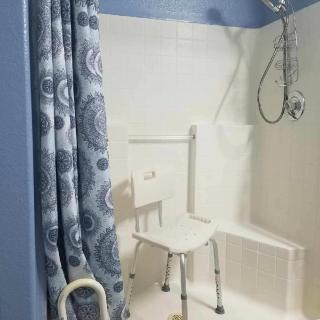 An accessible shower with a chair and grab bar for safety.