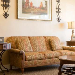 A cozy living room with a patterned sofa, side tables, and decorative wall art.