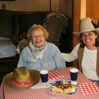 Two people sitting at a table with food, wearing hats and smiling.