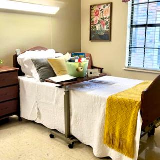 A cozy and well-arranged bedroom featuring a hospital bed with comfortable bedding and personal touches.