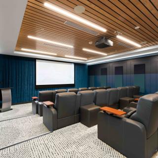 A modern home theater room featuring comfortable seating and a large screen.