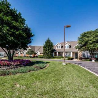 A well-maintained building surrounded by a lush landscape with trees and colorful flower beds.