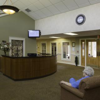A quiet waiting room with a reception desk, seating area, and a television mounted on the wall.