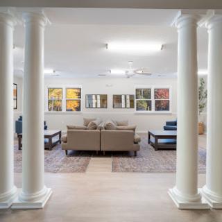 A modern living room featuring elegant columns, comfortable seating, and vibrant artwork.
