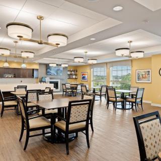 A modern dining area with neatly arranged tables and chairs, elegant lighting fixtures, and a welcoming atmosphere.