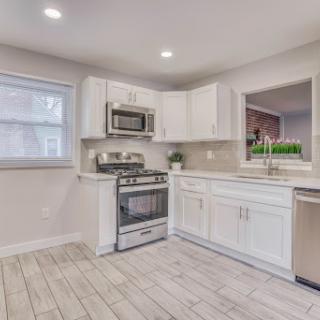 A bright and modern kitchen featuring white cabinetry and stainless steel appliances.
