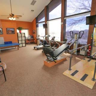 A spacious gym with various exercise equipment and large windows.