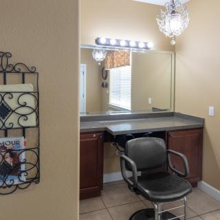 A well-lit hair salon styling area featuring a mirror, a black styling chair, and a chandelier.