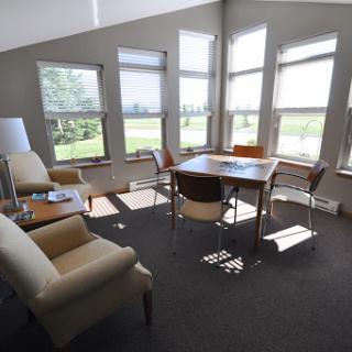 A bright and modern office space with ample natural light, featuring a table and comfortable seating.