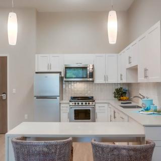A modern kitchen with white cabinets, stainless steel appliances, and pendant lighting.