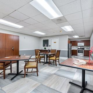 A communal kitchen area with tables and chairs, featuring a modern design and equipped with appliances.