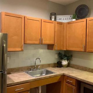 A modern kitchen featuring wooden cabinets and a sleek countertop with a stainless steel sink.