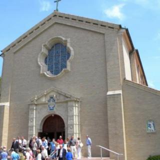 A group of people gathered outside a church on a sunny day.