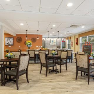 A well-lit dining area with neatly arranged tables and chairs, featuring tasteful decor and modern lighting.