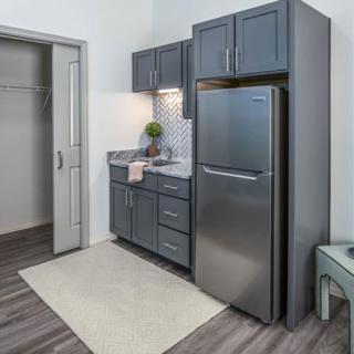 A modern kitchen setup with blue cabinets and a stainless steel refrigerator.