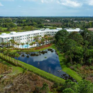 An aerial view of a hotel surrounded by lush greenery and a tranquil lake.