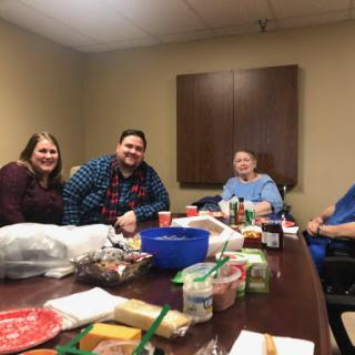 A cheerful gathering in an office space, enjoying food and good company.