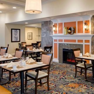 A cozy dining area with neatly set tables and a fireplace.