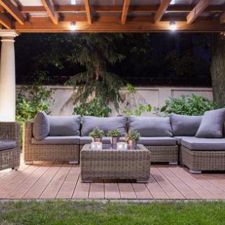 Cozy outdoor patio area with a sectional sofa under a pergola, illuminated at night.