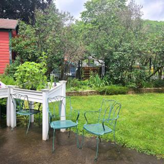A peaceful garden scene featuring green chairs and lush vegetation, with a hint of rain.