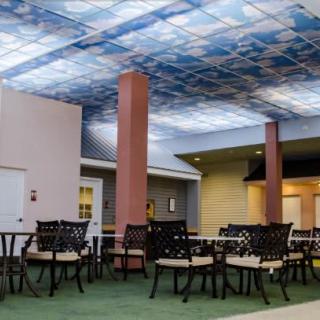 A modern indoor seating area with tables and chairs, featuring an artificial sky ceiling.