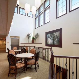 A modern interior space with a round table and chairs, large windows, and elegant decor.
