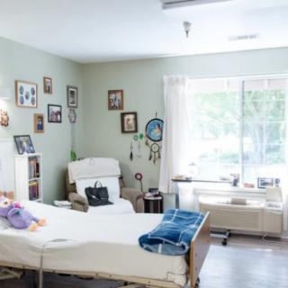 A well-lit hospital room with a bed, chair, and various decorations on the walls.