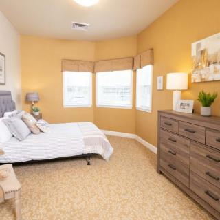 A cozy bedroom with warm yellow walls, featuring a comfortable bed and a wooden dresser.