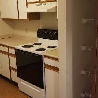 A compact kitchen with a stove and white cabinets.