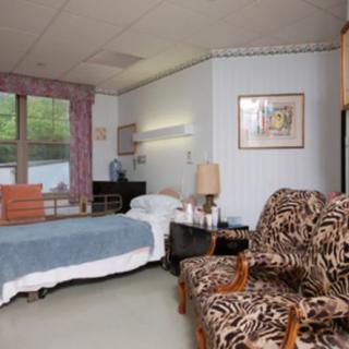 A hospital room with a bed, chairs, and various furnishings.