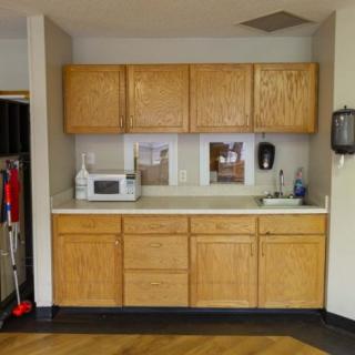 A simple kitchen setup with wooden cabinets and a microwave on the countertop.