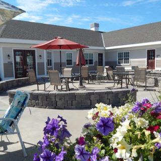 A sunny outdoor patio with tables and chairs, surrounded by colorful flowers.