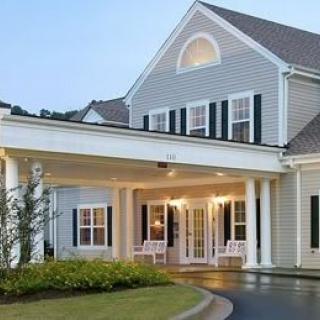 A colonial-style house with a covered entrance and white exterior.
