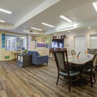 A cozy and well-lit communal living space with a dining area and seating arrangements.