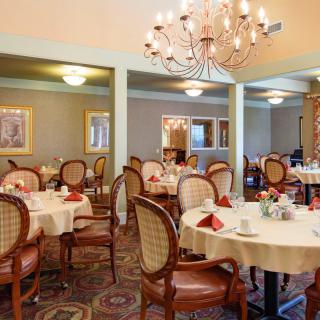 A formal dining area with elegantly set tables and a chandelier.