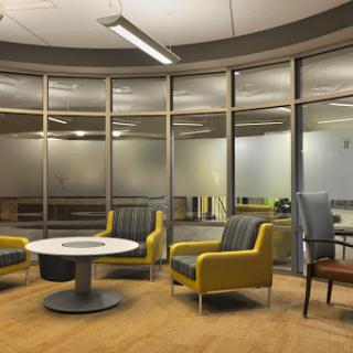 A modern office waiting area featuring contemporary furniture and glass walls.