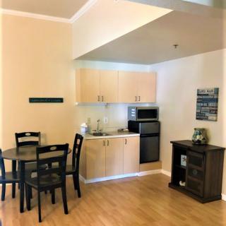 A small apartment kitchen with a dining area featuring a table and chairs, wooden cabinets, and basic appliances.