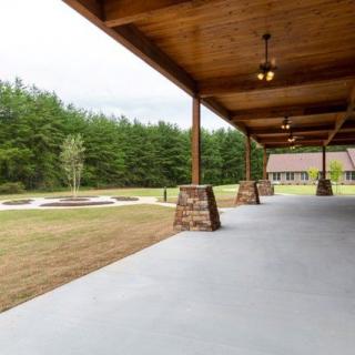 A spacious wooden-ceiling patio overlooking a lawn and wooded area.