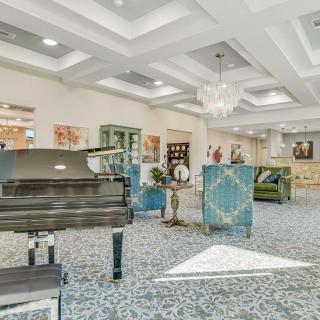 A luxurious and modern living room featuring a grand piano, elegant furniture, and stylish artwork.