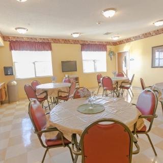 A community dining area with multiple round tables and red chairs arranged for seating.