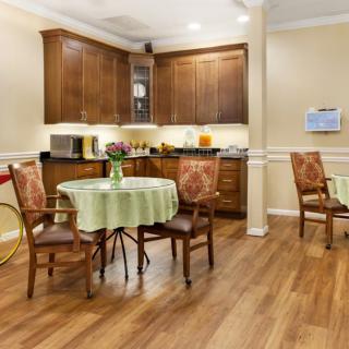 A cozy kitchen and dining area with wooden cabinetry and a table set for two.
