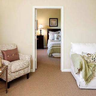 A cozy living room leading into a bedroom, featuring comfortable furniture and warm lighting.