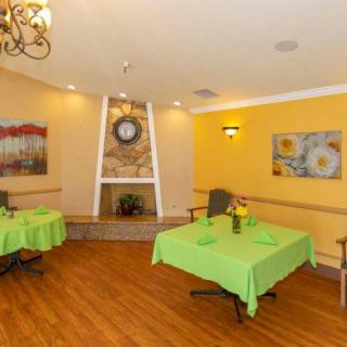 A cozy dining area with green tablecloths, a fireplace, and decorative art on yellow walls.