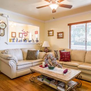 A cozy living room with a large sofa and coffee table, decorated with artwork and cushions.